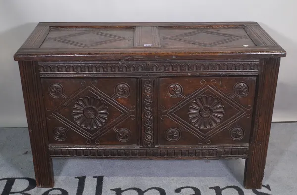 A 17th century carved oak coffer with twin panel lid and front on stile feet, 104cm wide x 63cm high.