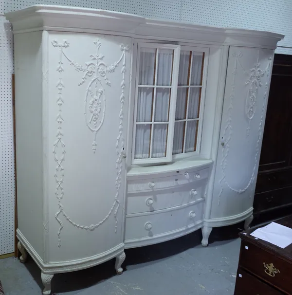 An early 20th century Continental white painted double bowfront wardrobe, with glazed two door middle section, flanked by bowed and swag moulded decor