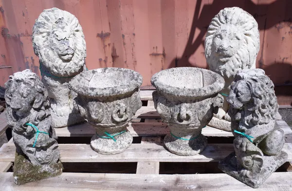 A pair of 20th century composition stone lions holding armorial shields, 30cm high, another pair of composition stone lions, 50cm high, and a pair of