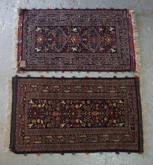 A Baluchistan rug, the black field with plants, flowers, spotted animals, a trailing floral black border, 127cm x 77cm; and a Baluchistan rug, the bla