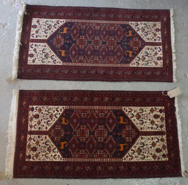 A pair of Baluchistan rugs, the black field with cross guls, four goats, ivory bird spandrels, 122cm x 65cm (2).