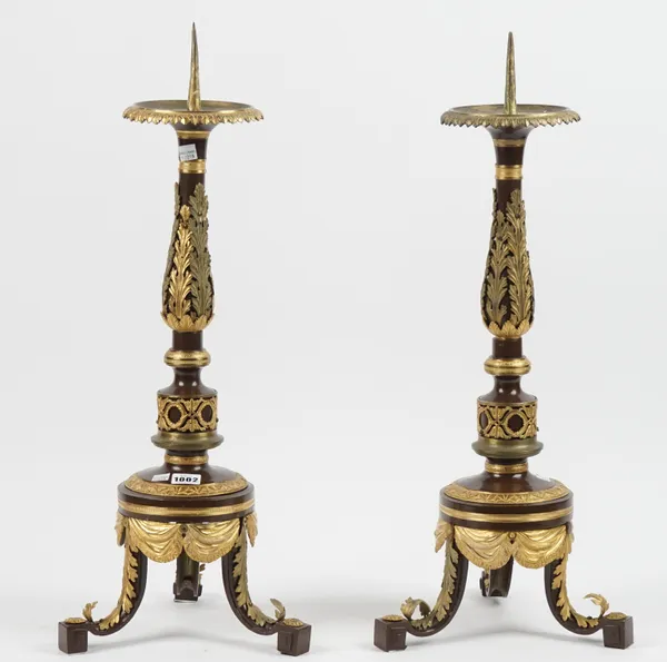 A pair of modern gilt and patinated metal altar candlesticks with acanthus moulded decoration over three shaped feet, 58cm high, (2).