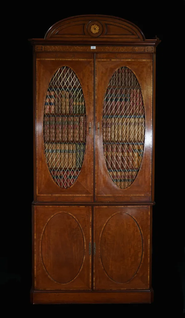 A Regency style inlaid mahogany bookcase cabinet with oval grille and faux book doors, 107cm wide x 233cm high.