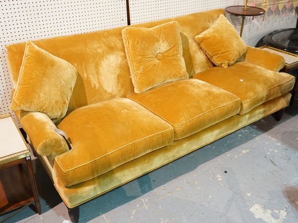 Baker; a modern three seater sofa with gold velvet upholstery, on ebonised tapering supports, 202cm wide x 84cm high and a matching low armchair, 90cm