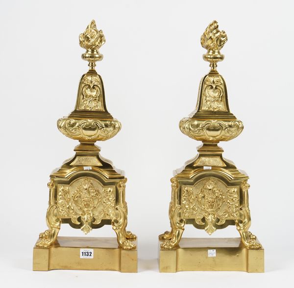 A pair of Louis XVI style gilt metal chenets, modern, each with flaming urn finial, foliate casting on four lion paw feet and a shaped base, 58.5cm hi