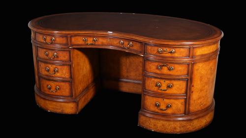 A modern mahogany kidney shaped pedestal desk with eight drawers and opposing cupboard base, with brown leather inset top, 180cm wide.