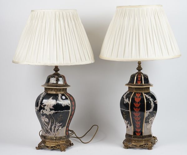 A pair of modern Chinese style pottery lamps, each modelled as an octagonal urn & cover decorated with flora & fauna, against a gilt black ground with