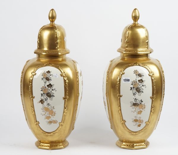 A pair of modern Italian porcelain vases and covers, with decorated panels against a gilt moulded ground, 60cm high, (2).