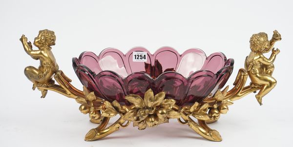 A Christofle amethyst glass mounted gilt metal centrepiece bowl with twin cherub handles and a pierced foliate frame, stamped marks, 54cm wide.