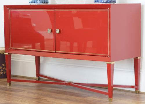 A modern red lacquer side cabinet,  on tapering square supports, united by 'X' frame stretcher, 135cm wide x 86cm high.