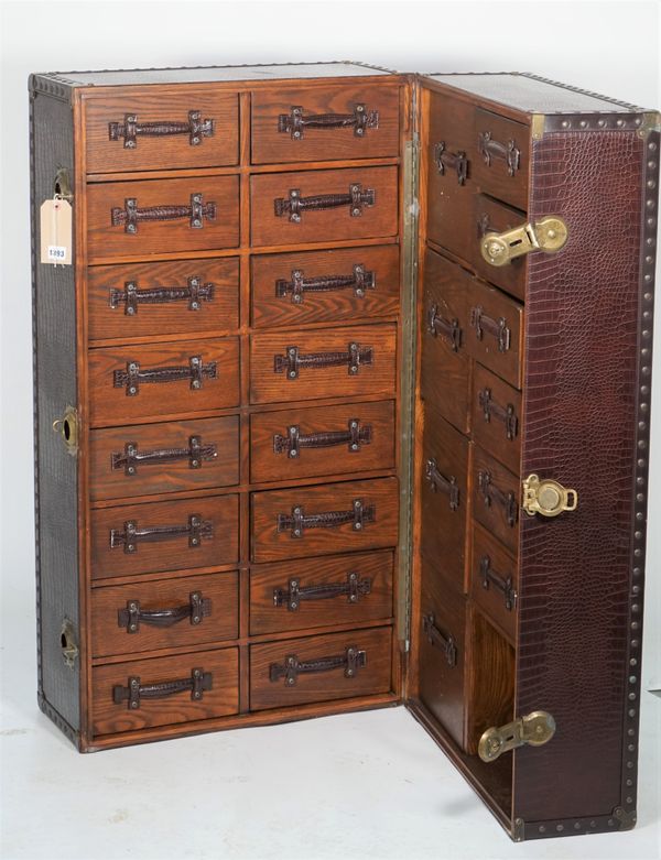 A modern faux crocodile skin upholstered upright travelling trunk fitted with thirty-two short drawers, 46cm wide x 118cm high.