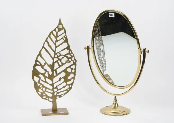 An oval brass swing frame mirror, 60cm high and a fret cut metal leaf ornament, 56cm high, (2).