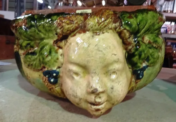 A Continental pottery wall fountain basin, late 19th/20th century, moulded in high relief with the face of a youth flanked by fruiting branches, 28cm