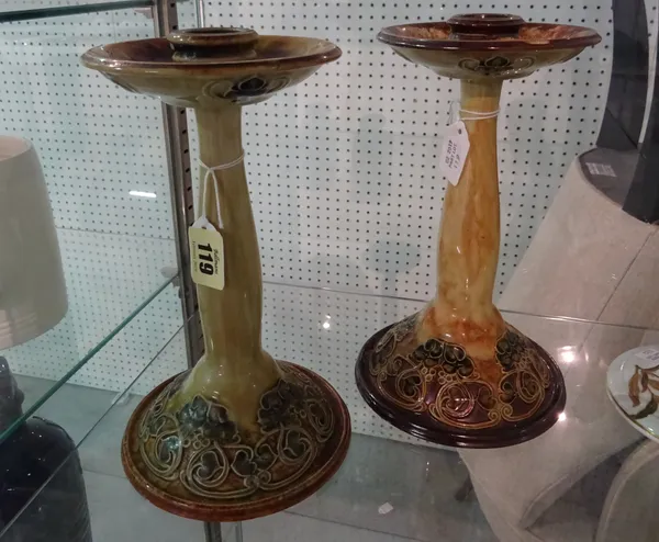 A matched pair of Royal Doulton stoneware candlesticks, Art Nouveau foliate decoration with oversized circular drip pans over a tapering stem and wide