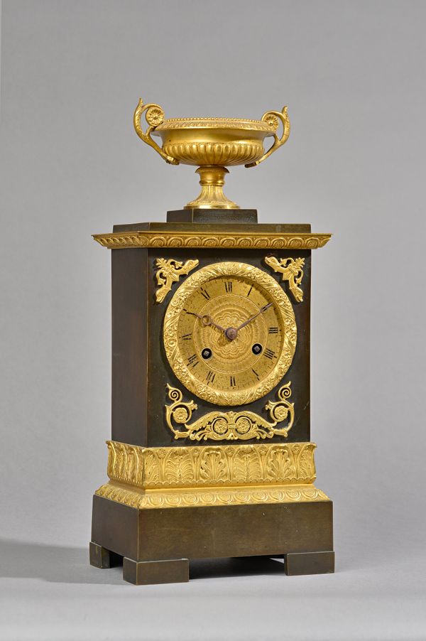 A French Empire style ormolu mounted bronze mantel clock, C.1860, with an urn surmount over a rectangular body enclosing a two train movement with cou