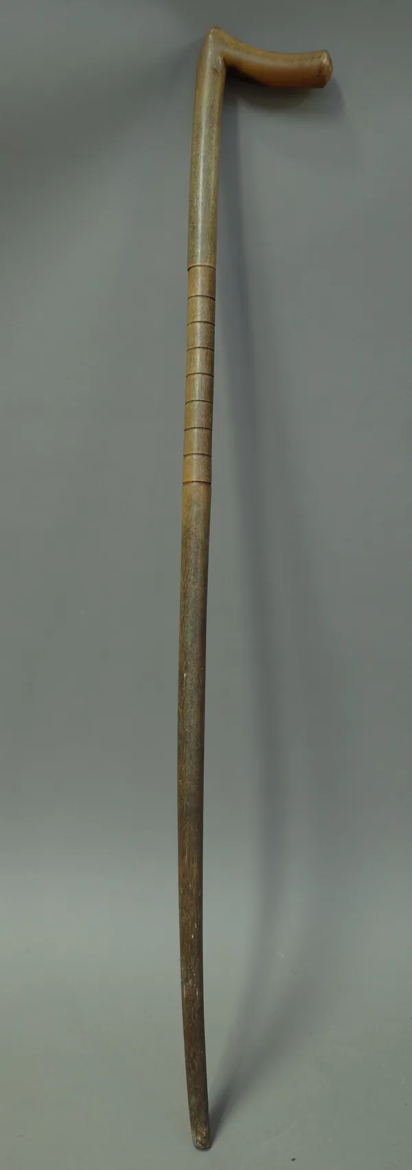 A rhinoceros horn walking stick, late 19th century, of sectional form with carved bands to the shaft. 84cm.