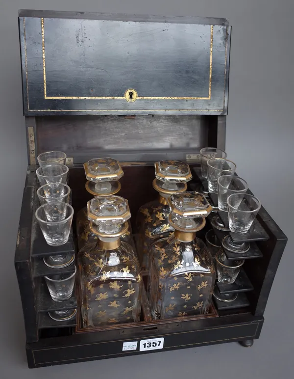 A late 19th century ebonised rosewood and brass inlaid liquor cabinet containing four gilt decorated decanters and a part suit of glassware, (incomple