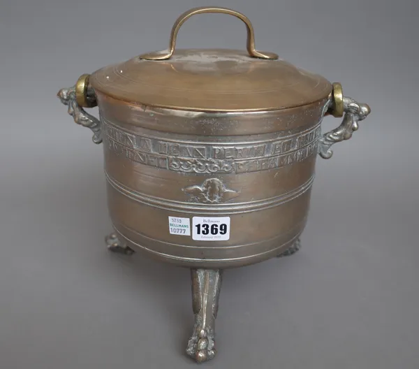 A white metal and brass mounted cooking pot and cover with swingover handle, possibly 18th century, raised on three lion paw feet, relief cast with La