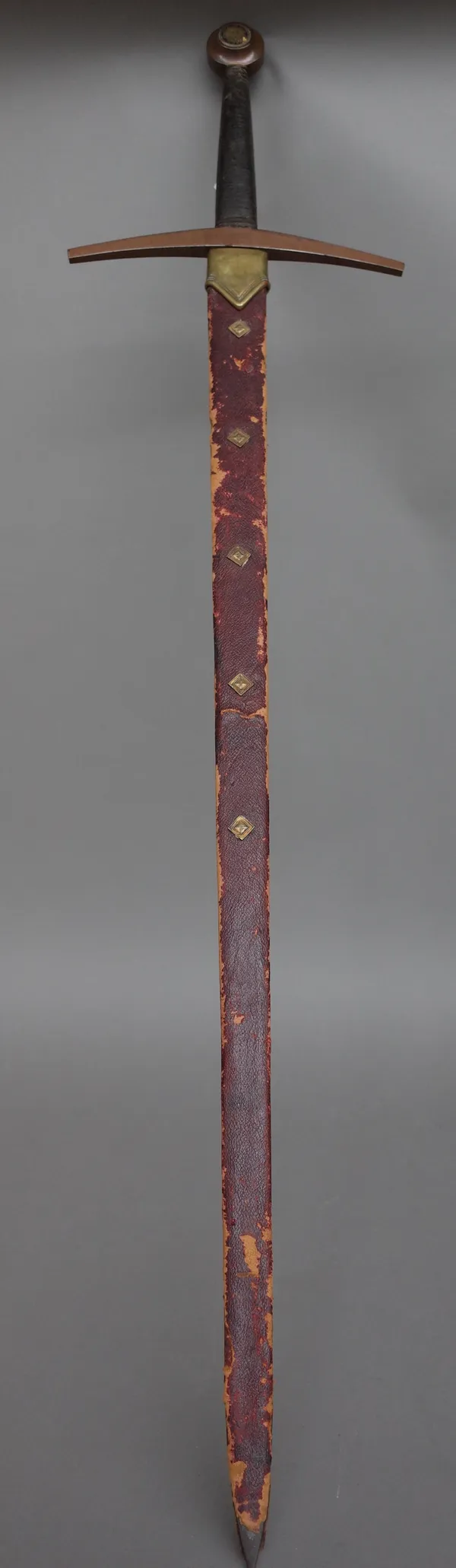 A 20th century ceremonial broad sword with double edged steel blade, 91cm, cross guard hilt, wire bound grip and lions head detail to the circular pom