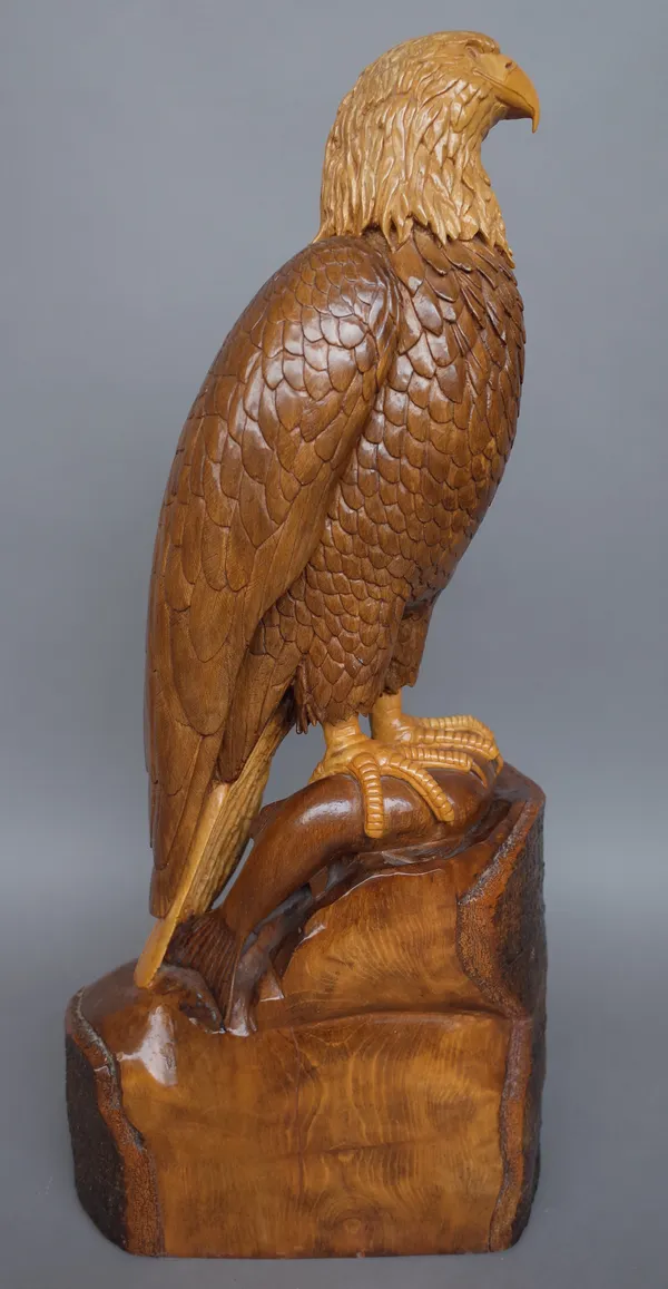 Ian Brennan, a beechwood carved sculpture depicting a bald eagle with salmon on a naturalistic base, signed and dated 1986, 67cm high.