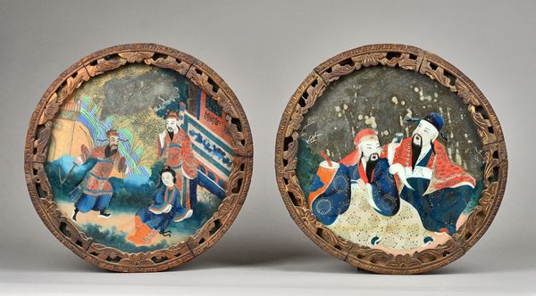 A pair of Chinese reverse painted pictures on glass, 19th century, each depicting Chinese figures at leisure in a gilt carved circular wooden frame, 4