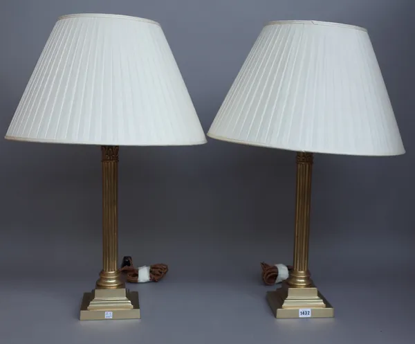 A pair of Victorian style brass table lamps, each of Corinthian column form on a stepped square base, with cream pleated shades, 71cm high overall. (2