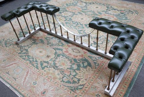 A Victorian style polished steel, brass and faux leather club fender with green button back seat and pillared rail over a shaped kerb, 169cm wide.