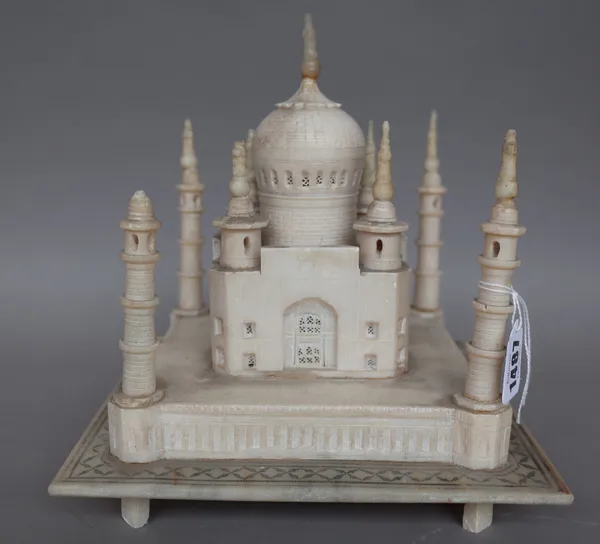 A carved alabaster model of the Taj Mahal, India, circa 1900, on a square plinth and four feet, (a.f.), 23cm wide.