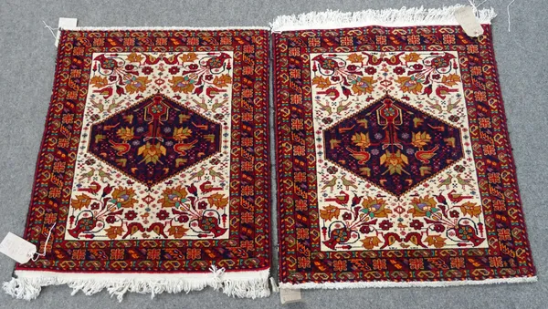 A pair of Baluchistan mats, the ivory field with an indigo diamond, all filled with single flower vases and birds, 65cm x 75cm, (2).