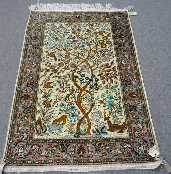 A silk Ghom tree of life rug, Persian, the ivory field with entwined trees, with birds, flowers, animals; a brown palmette leaf-spray and bird border,