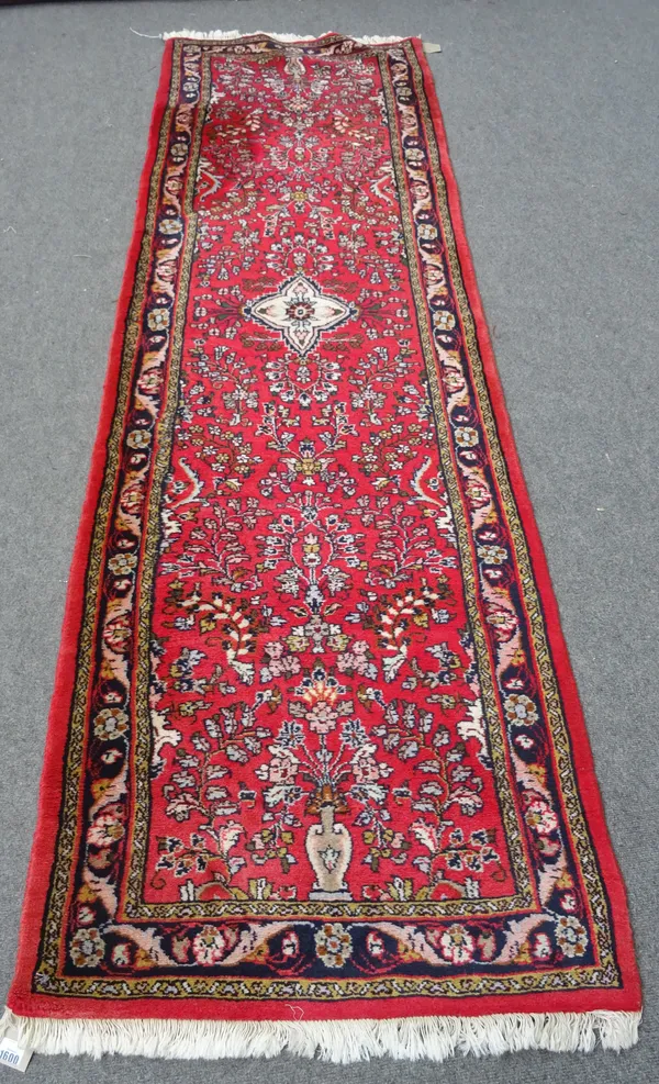A Hamadan runner, the madder field with an ivory medallion, all with floral sprays, a black floral border, modern, 280cm x 80cm.