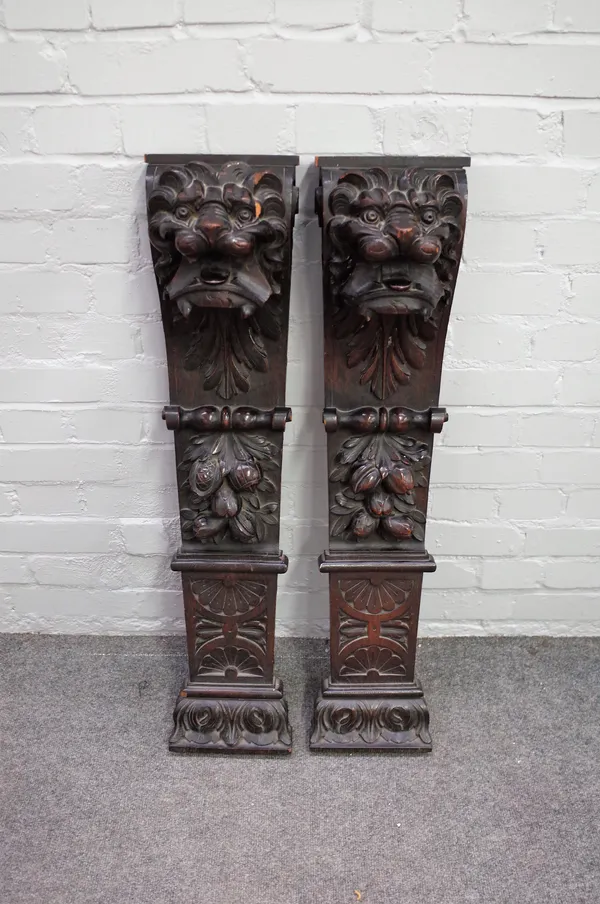 A pair of 19th century carved oak pilasters, each decorated with lion mask and fruit, 20cm wide x 93cm high.