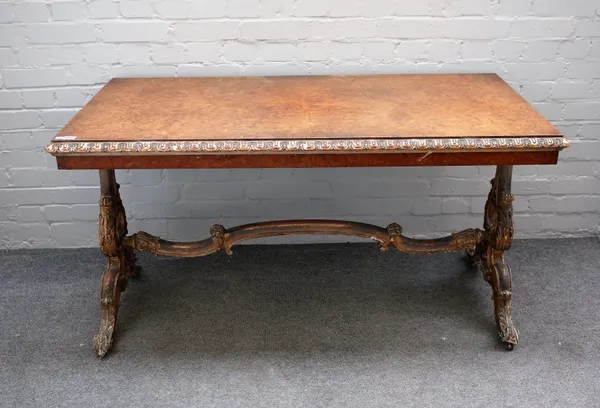 A Victorian parcel gilt figured walnut rectangular centre table on carved trestle end standards and four scroll supports, 139cm wide x 73cm high.