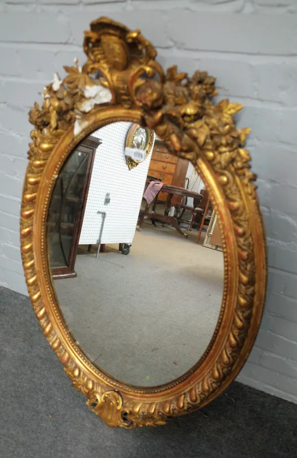 A mid-19th century gilt framed mirror, with opposing cherub crest above oval plate, 72cm wide x 108cm high.