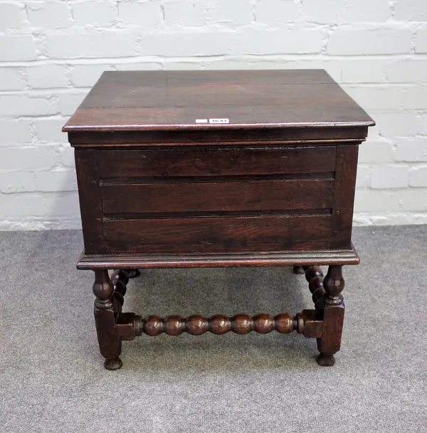 A 17th century oak box stool on block and turned supports, 50cm wide x 53cm high.
