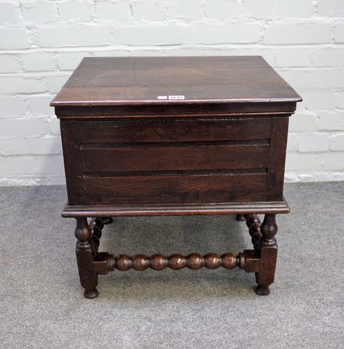 A 17th century oak box stool on block and turned supports, 50cm wide x 53cm high.