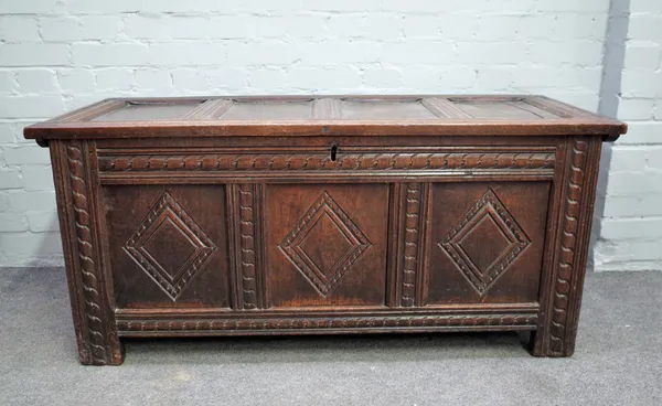 An 18th century oak coffer, the side pivot four panel lid over carved triple panel front, 131cm wide x 60cm high.