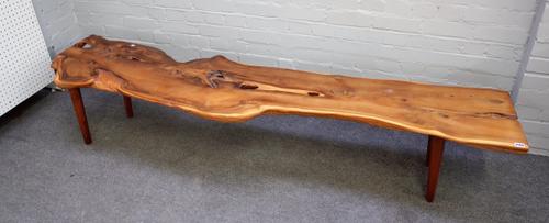 Reynolds of London, a 20th century low side table, the naturalistic yew wood plank top on turned supports, 214cm wide x 40cm high.