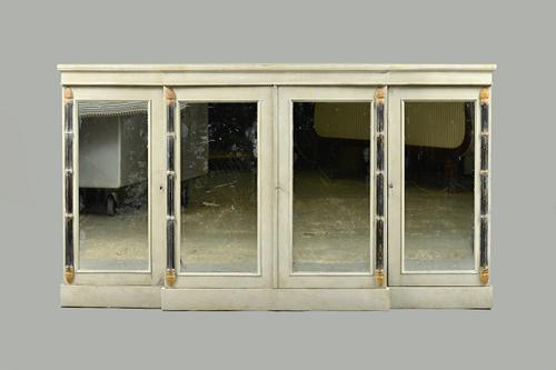 A 19th century later painted breakfront side cabinet with four mirrored doors, divided by ebonised cluster columns, 182cm wide x 102cm high. Illustrat