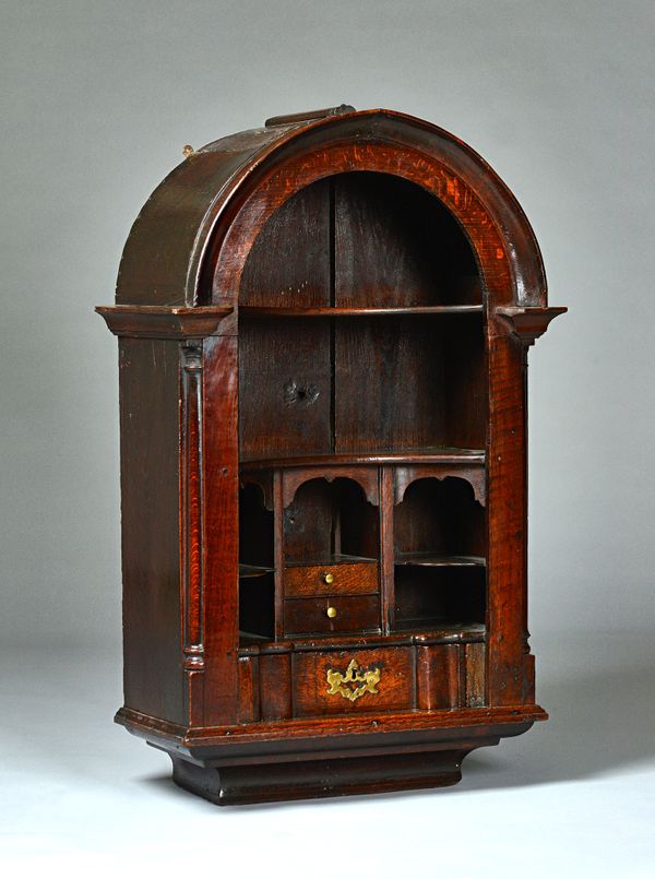 An unusual 18th century Welsh oak bonnet top hanging cupboard with an arrangement of concave shelves, drawers and secret compartments, 65cm wide x 104