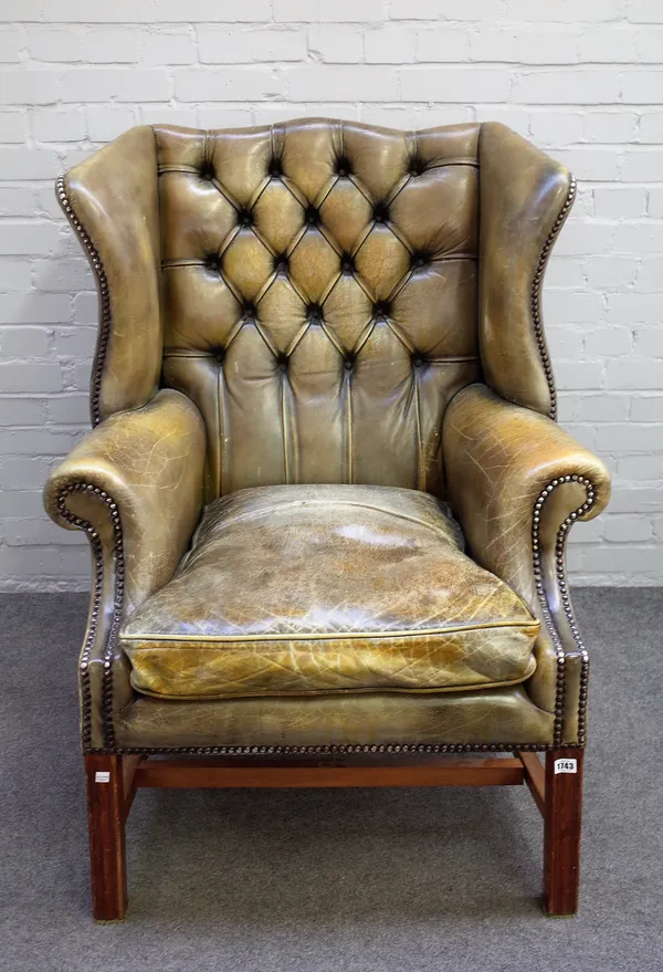 A George II style green leather upholstered brass studded wingback armchair on channelled block supports, 85cm wide x 110cm high.