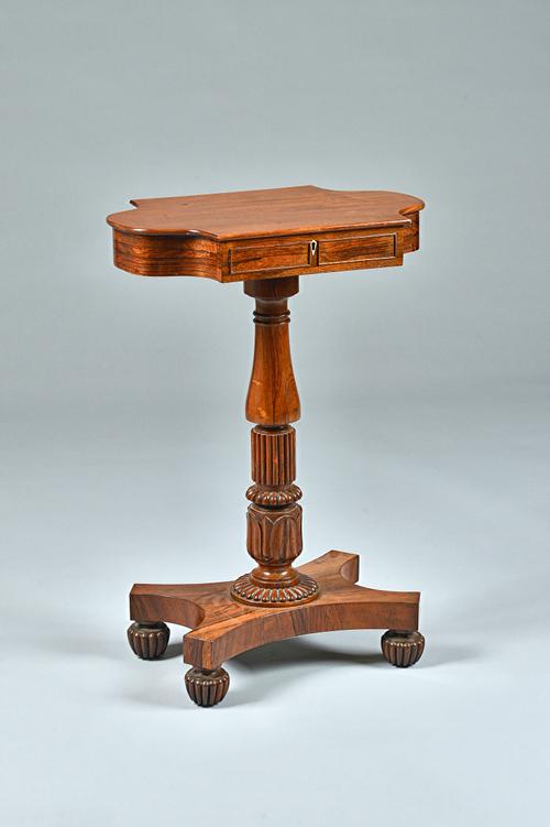 In the Manner of Gillows, a mahogany and rosewood side table, the shaped single drawer top on baluster turned and reeded column and quatrefoil platfor