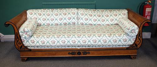A Biedermeier walnut part ebonised free standing daybed with rollover arms and spindle turned back, 236cm wide x 74cm high.