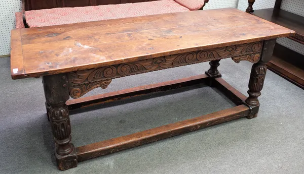 A 19th century oak refectory table, incorporating 17th century elements, the cleated plank top over carved frieze and turned supports united by perime