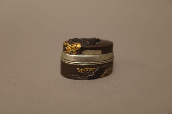 A Japanese inlaid fuchi-kashira 19th century, converted to a box and cover with silver coloured mounts, inlaid in gilt with a bear amongst leafy branc