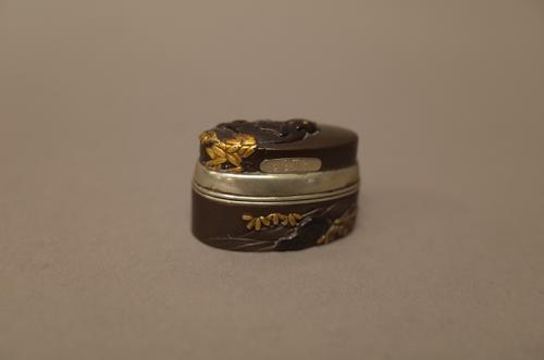 A Japanese inlaid fuchi-kashira 19th century, converted to a box and cover with silver coloured mounts, inlaid in gilt with a bear amongst leafy branc
