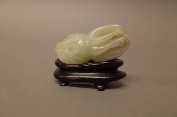 A Chinese celadon jade carving of a finger citron, 19th/20th century, 5.5cm. length, wood stand, (2).