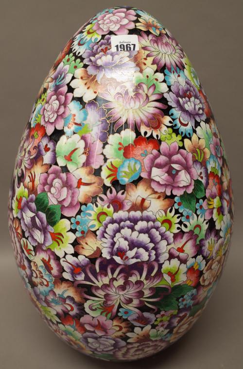 A very large Chinese cloisonné egg, worked with colourful flowers against a black ground, 52cm. high.