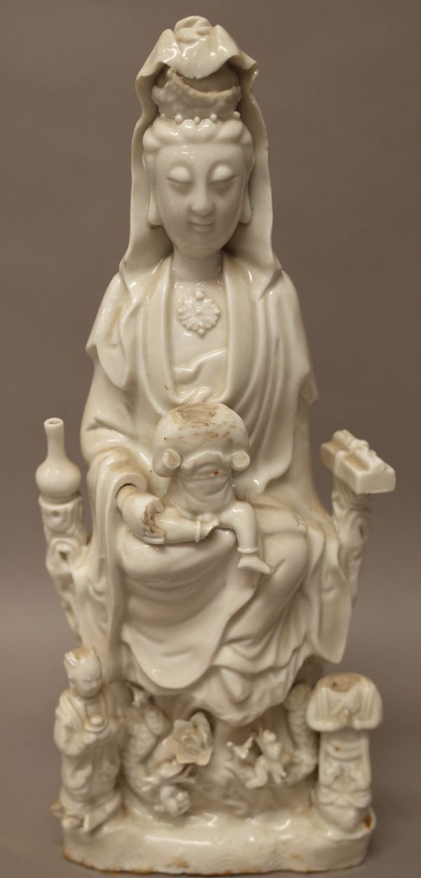 A Chinese blanc de chine figure of Guanyin, 18th/19th century, modelled seated with a boy on her lap and two acolytes standing below, (a.f), 37cm. hig