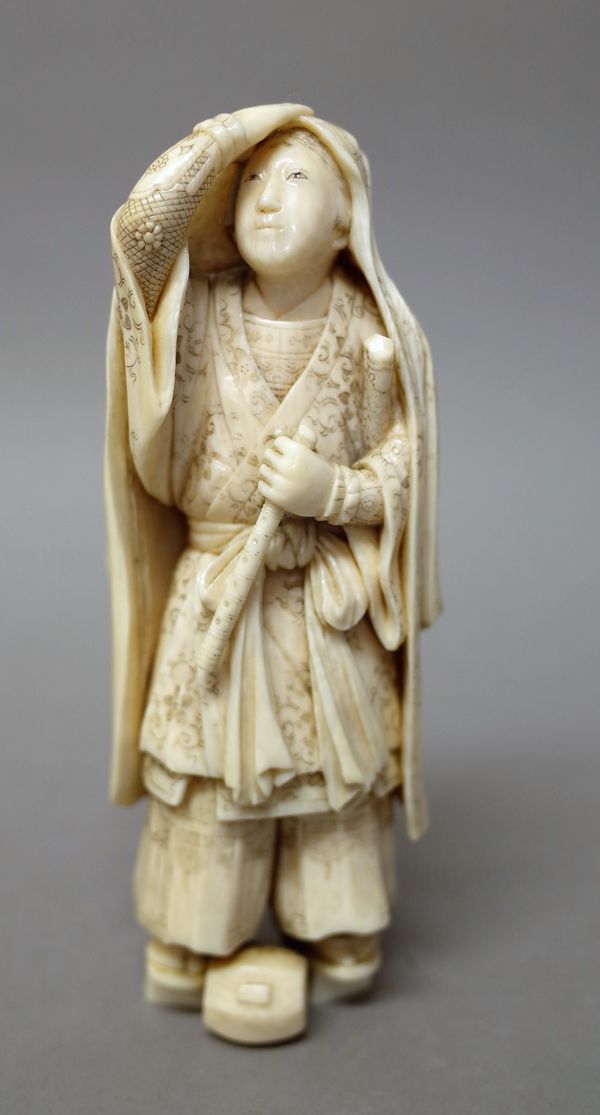 A Japanese ivory okimono of Ushiwaka-maru, Meiji period, signed Tomotsugu, standing with right hand held to his head, his left hand clutching a flute,